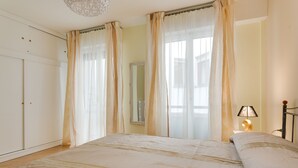 A bedroom with a large bed, curtains, a bedside lamp, and a wardrobe.