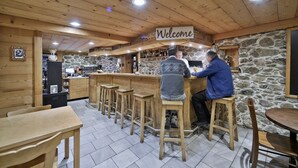 Un coin bar au style rustique, avec des meubles en bois et un mur en pierre en arrière-plan.