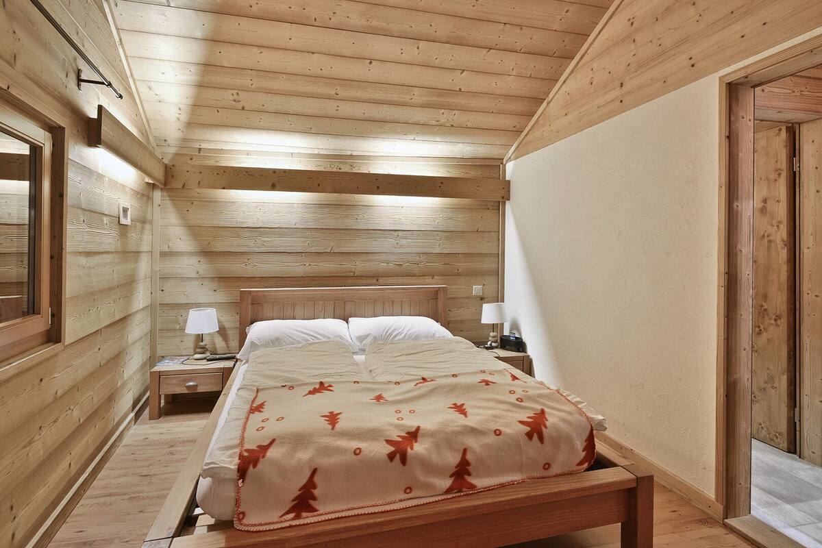 Une chambre dans une cabane en bois, avec un lit, des tables de chevet et une porte.