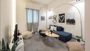 A modern living room with a sofa, a coffee table, a TV, and a lamp. - Cosy apt near Piraeus central port, Mikrolimano port & Pasalimani port. (Pireas)