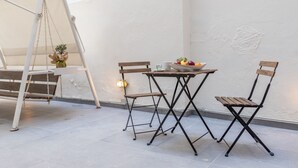 A small outdoor seating area with a table and two chairs, a hanging chair, and a potted plant. - Cosy apt near Piraeus central port, Mikrolimano port & Pasalimani port. (Pireas)