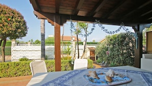An outdoor patio with a table set for two, featuring a decorative plate with seashells.