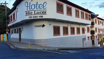 Um edifício de dois andares com uma placa que diz "Hotel São Lucas" e uma seta de recepção apontando para a direita.