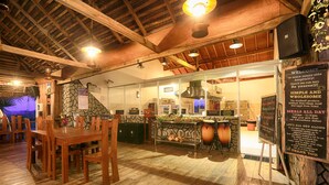L’intérieur de ce restaurant rustique se caractérise par un plancher en bois, des poutres apparentes et un mur en pierre.