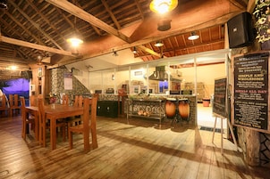 Interior rústico de restaurante con pisos de madera, vigas a la vista y una pared de piedra.