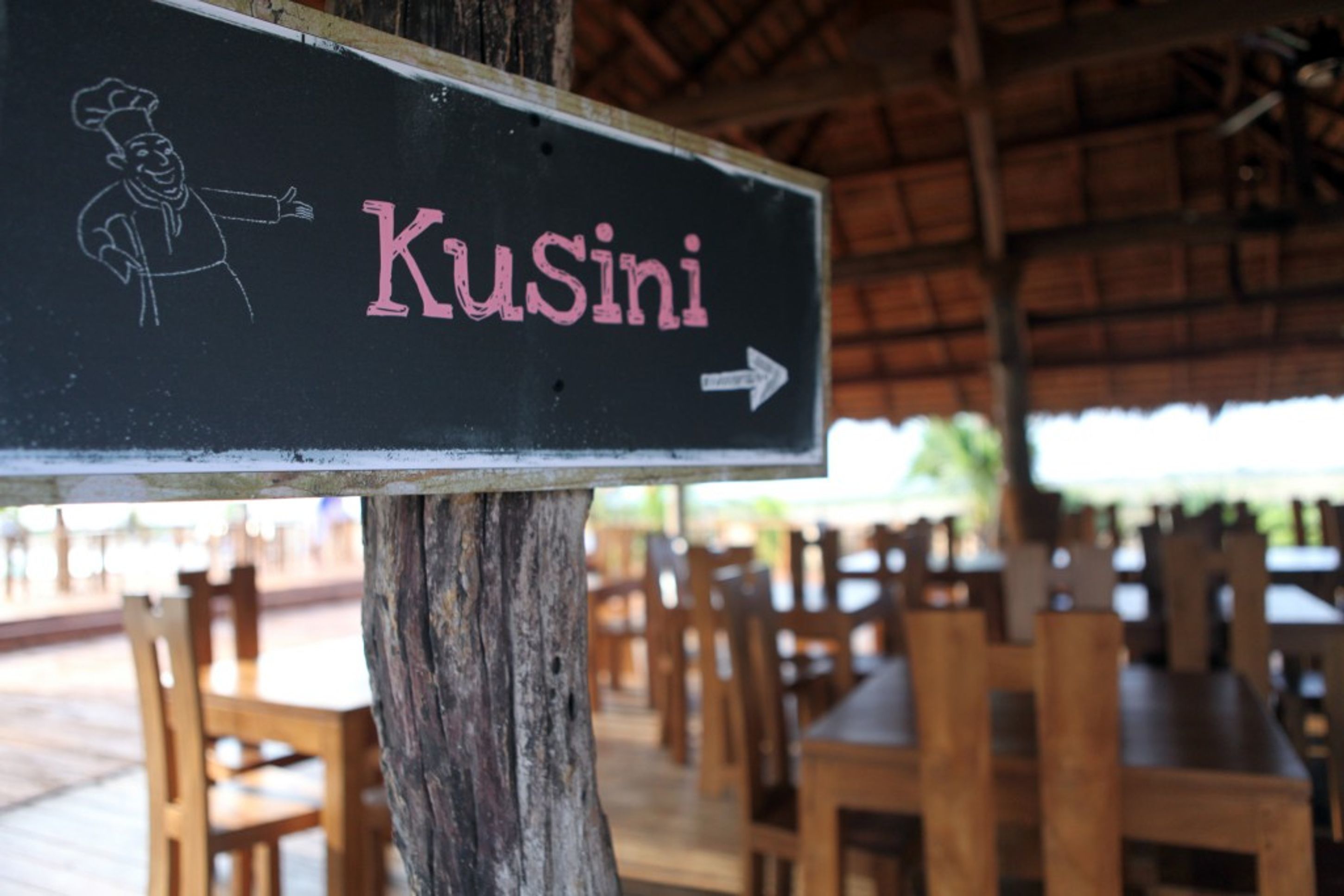 A sign with the word "Kusini" and an arrow pointing to the right, mounted on a wooden post.