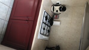 A kitchen with a red cabinet, a gas stove, a coffee maker, and a kettle. - Grand t 2 on Bastia (Bastia)