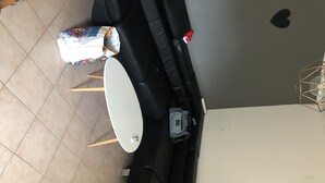 A modern living room with a black sofa, a white coffee table, and a small black table. There is a patterned bag on the sofa and a grey bag on the table. - Grand t 2 on Bastia (Bastia)