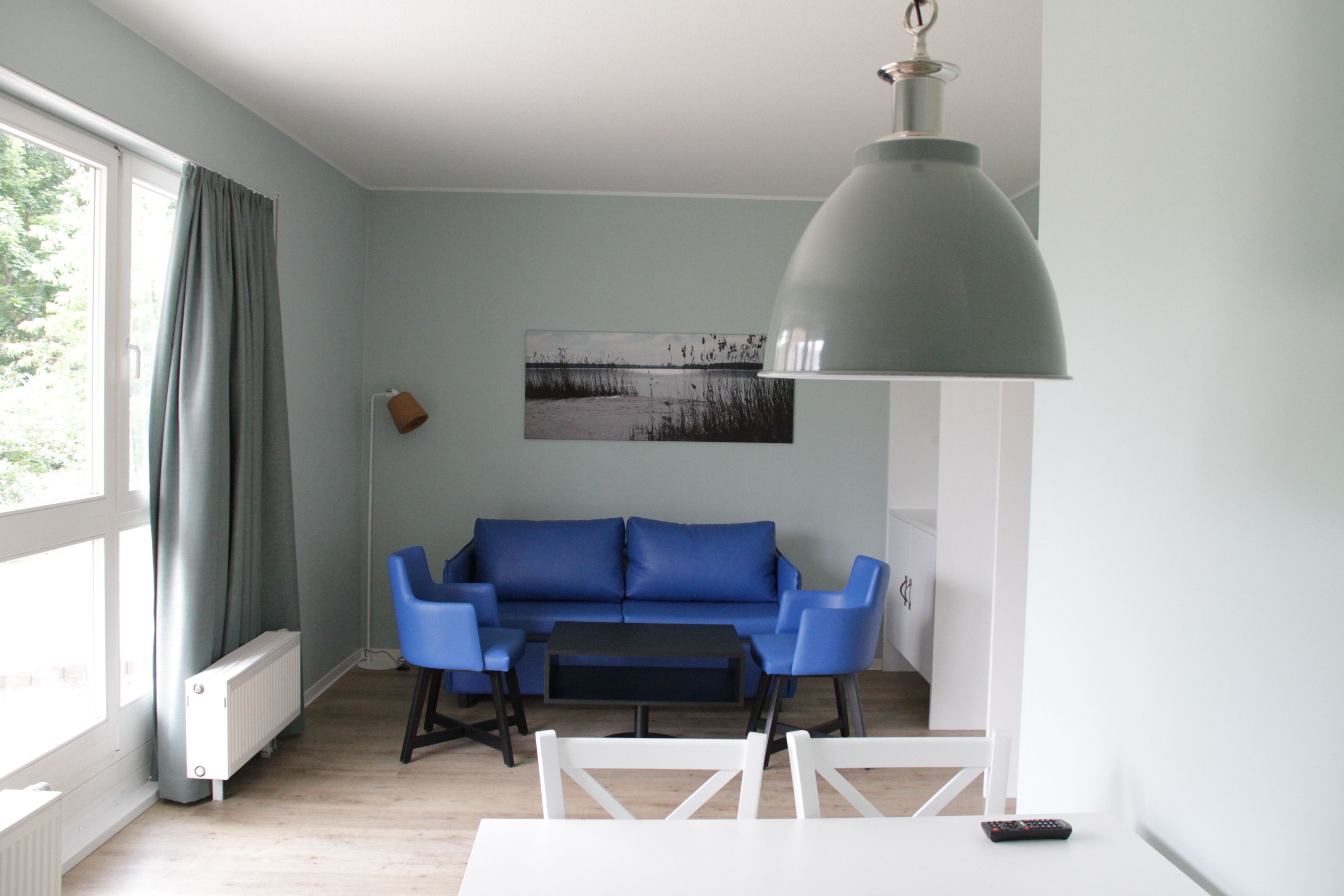 A living room with a blue sofa, a white coffee table, and a pendant light.