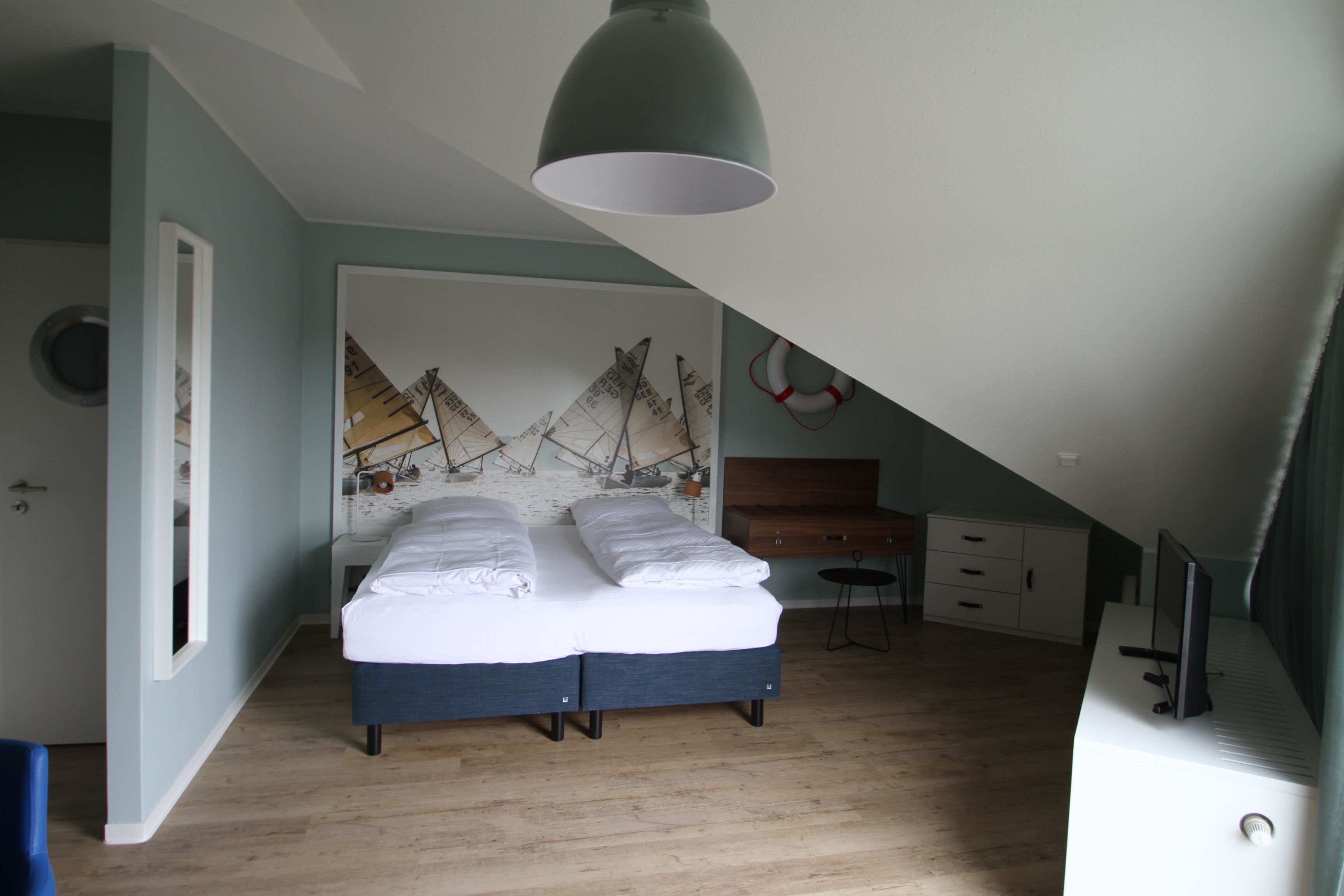 Un dormitorio con cama, escritorio, silla y estante en la pared.