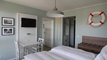 Un dormitorio con cama, un escritorio, una silla, un televisor y un flotador en la pared.