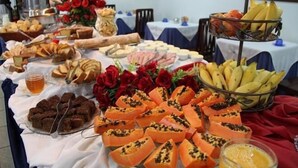 A buffet table with various food items including bread, pastries, and fruits. - Js Palace Hotel (Alfenas)