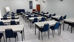 A conference room with multiple tables and chairs, a whiteboard, and a podium. - Js Palace Hotel (Alfenas)