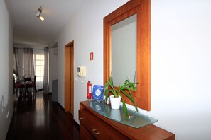 Ein Hotel-Empfangsbereich mit einem Holztisch, einer Topfpflanze, einem Feuerlöscher, einer Uhr und einem Schild mit 9,6 % Rabatt.