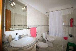 Un baño con lavamanos, espejo, inodoro, bidé y cortina de ducha.