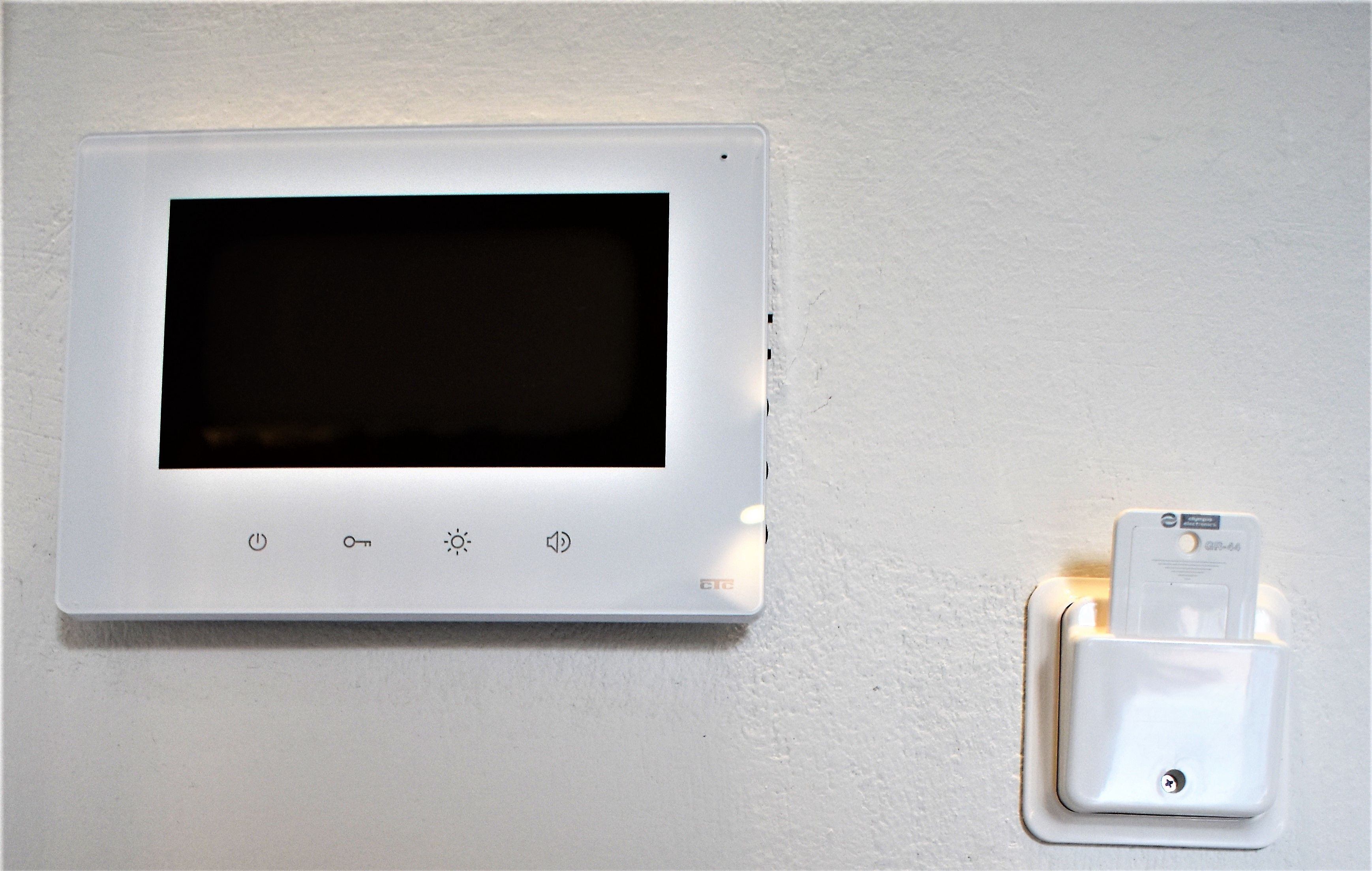 A thermostat with a control panel and a wall-mounted plug.