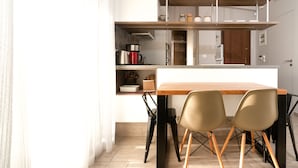 A modern kitchen with a wooden table and two chairs, a built-in oven, and a shelf with jars. - Acropolis Suites (Athens)