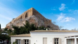 A building with a stone structure and a tiled roof. - Acropolis Suites (Athens)
