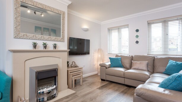 A living room with a fireplace, a sofa, and a television. - Angel Mews (Poole)