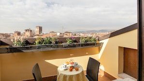 A balcony with a table set for breakfast, overlooking a cityscape with historic buildings and a clear sky. - Scaligerorooms (Verona)