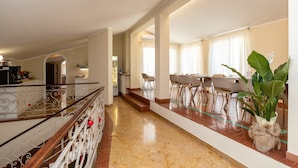 A spacious hallway with a marble floor, a staircase, and a dining area with chairs and tables. - Scaligerorooms (Verona)