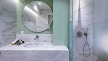 A bathroom with a marble sink, a round mirror, and a shower.