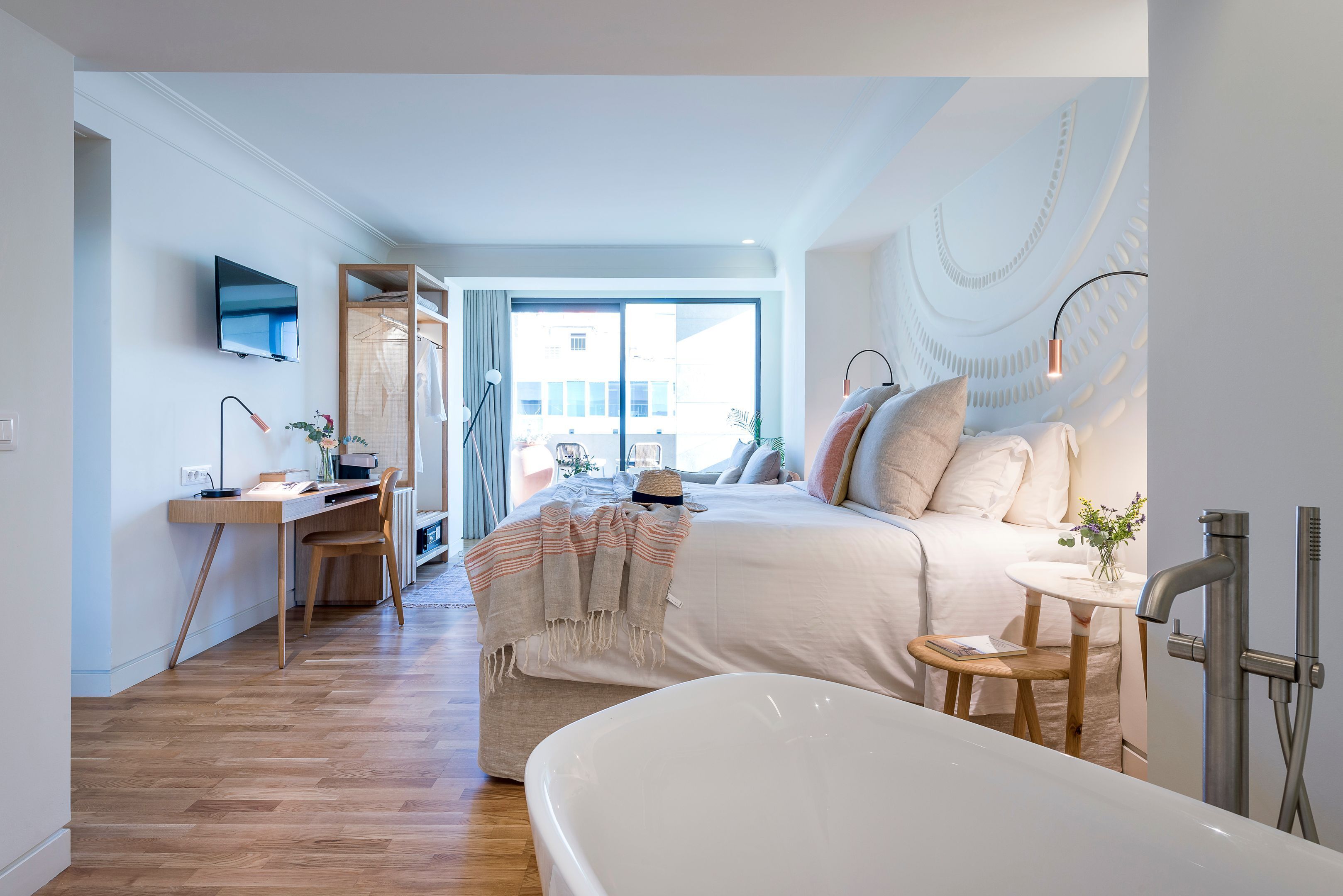 Camera da letto moderna con un letto grande, una scrivania, un televisore e un bagno con vasca e doccia.