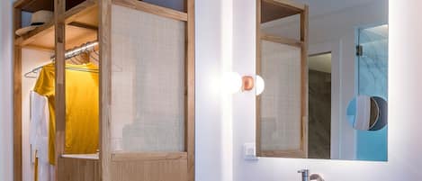 Un baño moderno con un tocador de madera, un espejo grande y un estante empotrado con toallas.