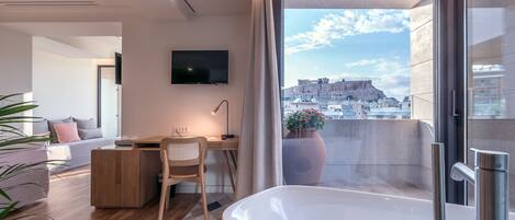 A modern living room with a large bathtub, a desk, and a TV.