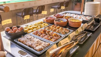 Een buffet met aangeduide gerechten, waaronder gekookte eieren, omeletten en diverse broden.