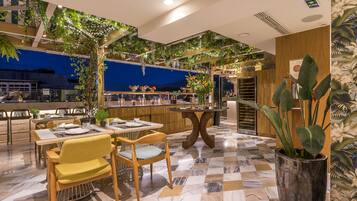 Un restaurant moderne avec un sol à carreaux, des meubles en bois et des plantes d’intérieur.