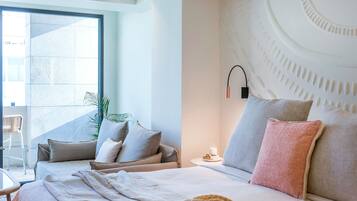 Un hotel moderno con una cama grande, una mesita de noche, una lámpara de pared y vistas amplias por una ventana grande.
