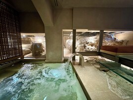 Un área de spa con hidromasaje, paredes de piedra y una zona de estar.