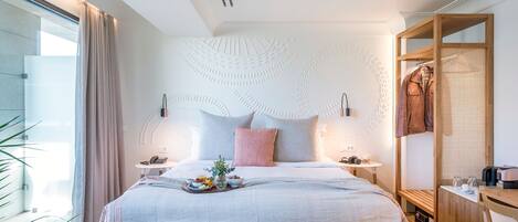 A modern hotel room with a large bed, bedside tables, a wooden wardrobe, and a view of the outdoors.