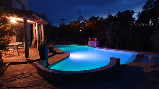 Ein Schwimmbecken mit Holzterrasse und überdachter Veranda.