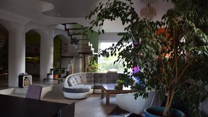 Ein modernes Wohnzimmer mit einem Ecksofa, einem Couchtisch und einer großen Topfpflanze.