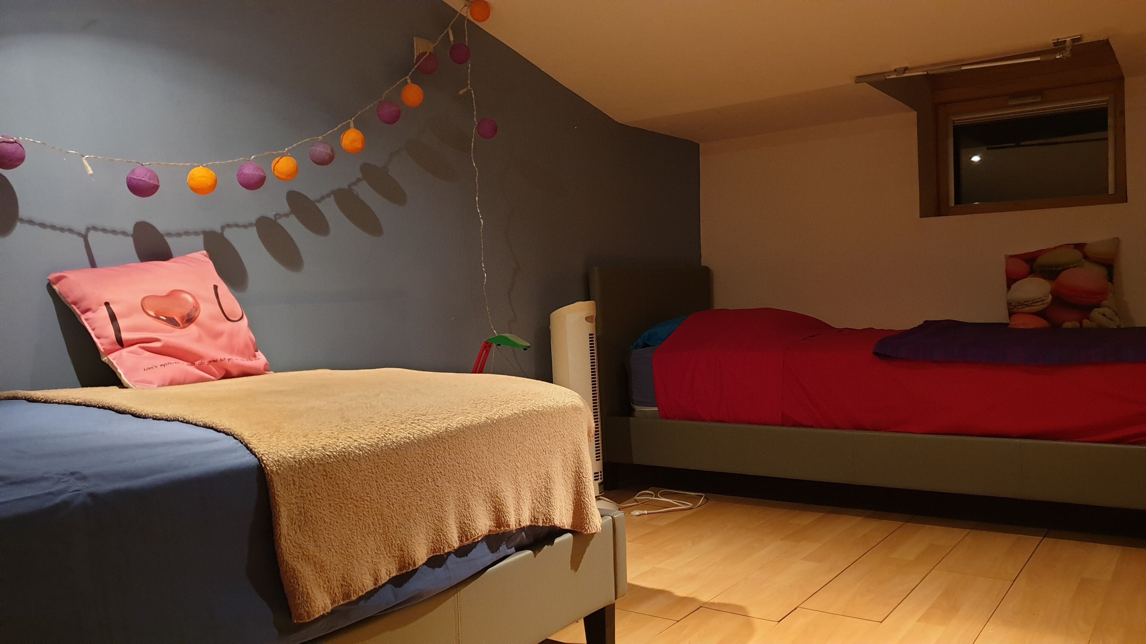 Ein Schlafzimmer mit zwei Betten, einem Fenster und einem an der Wand befestigten Regal.