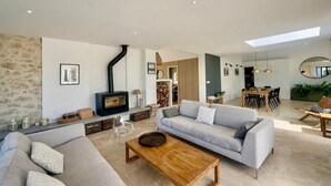 Een moderne woonkamer met een open haard, een bank, een bijzettafeltje en een eethoek.