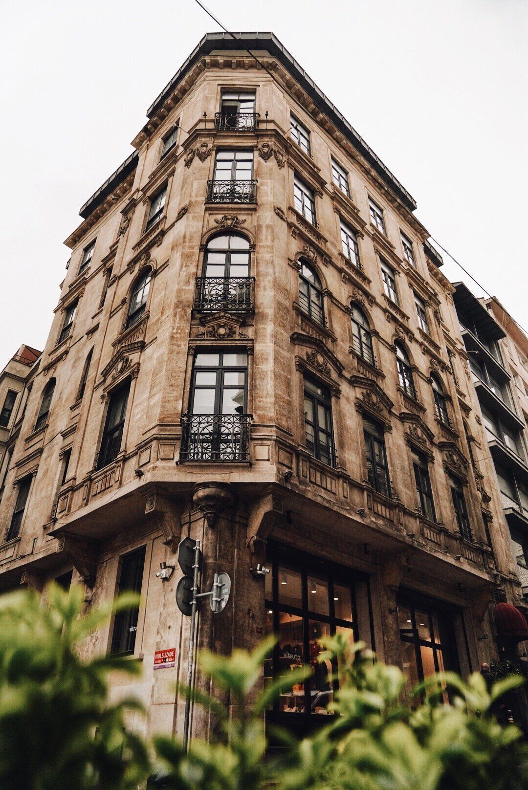 A corner building with multiple windows and balconies, featuring a classic architectural style.