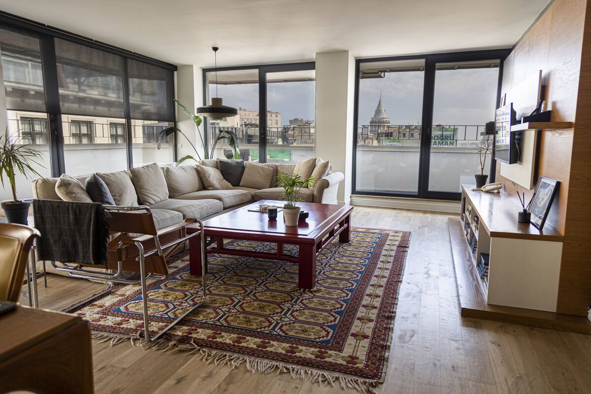 A modern living room with a sofa, coffee table, and large windows offering a city view.