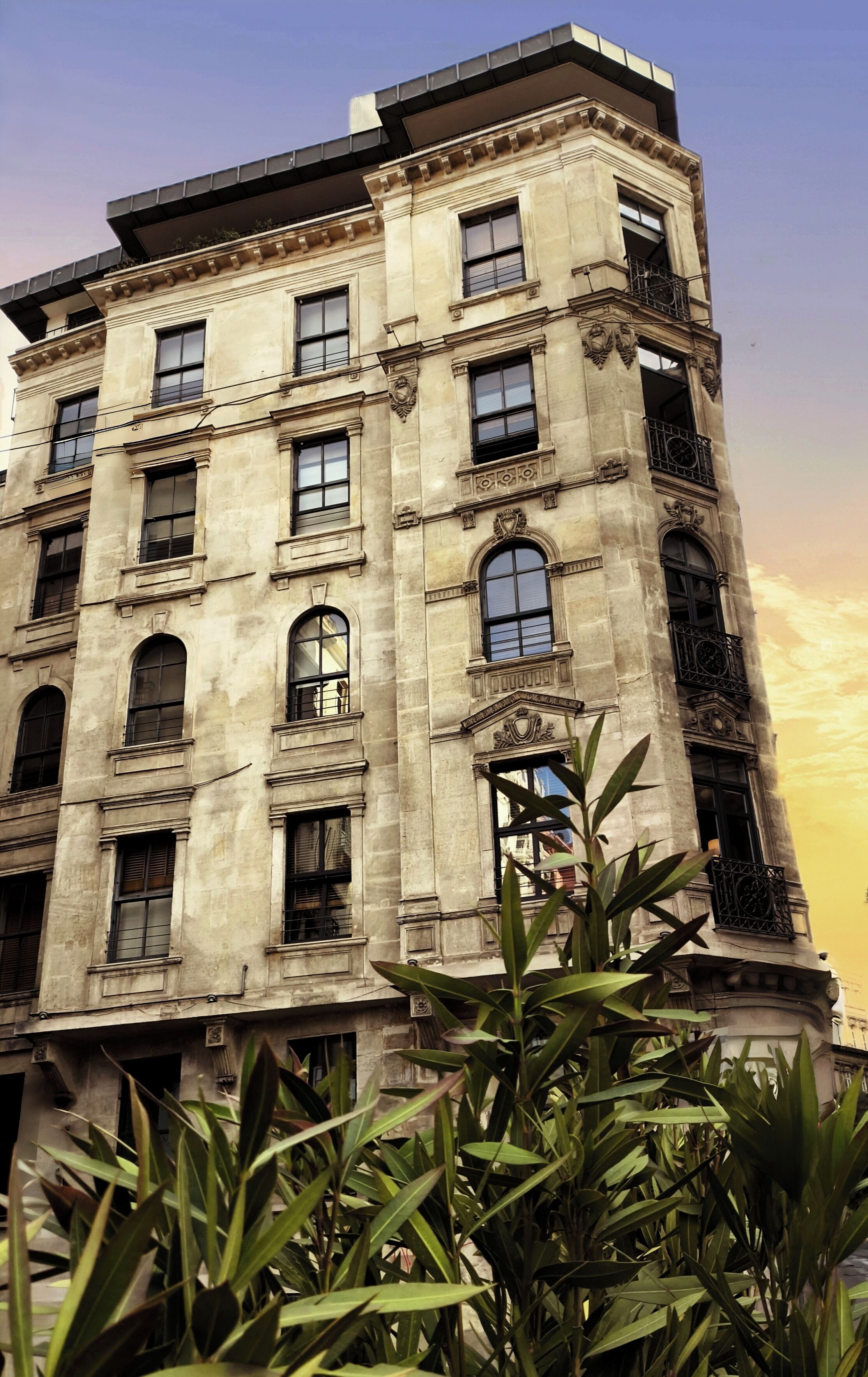 Un edificio de varios pisos con arquitectura clásica, que presenta ventanas de arco y molduras decorativas.