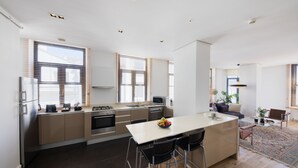 A modern kitchen with a central island, stainless steel appliances, and a dining area with a glass table and chairs. - GALATA M84  (Istanbul)