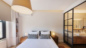 A modern bedroom with a large bed, bedside tables, a bookshelf, and a sliding glass door to a bathroom. - GALATA M84  (Istanbul)