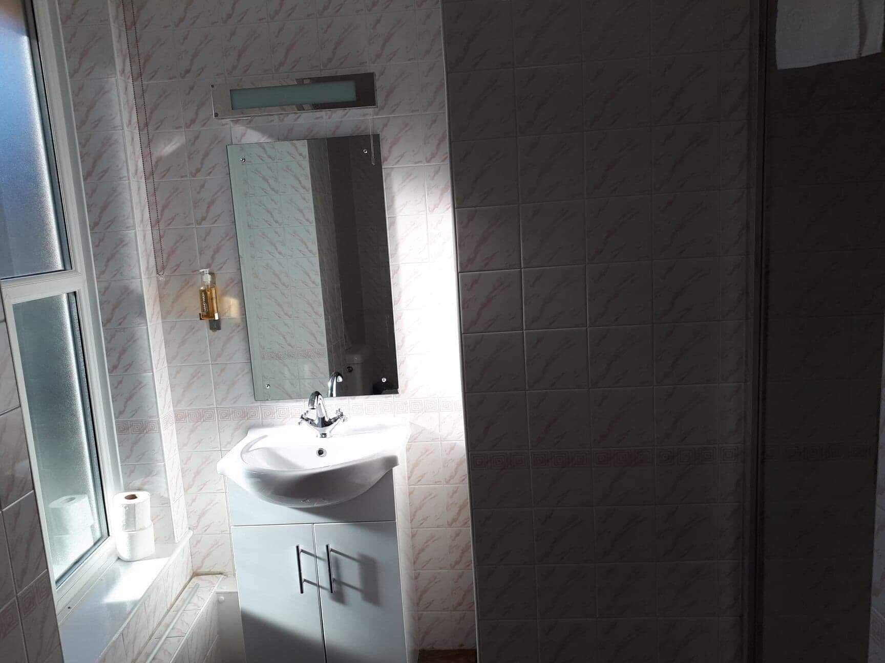 Une salle de bain avec un lavabo blanc, un miroir et des toilettes.