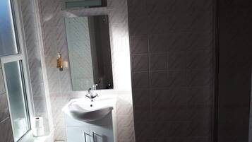 Une salle de bain avec un lavabo blanc, un miroir et des toilettes.