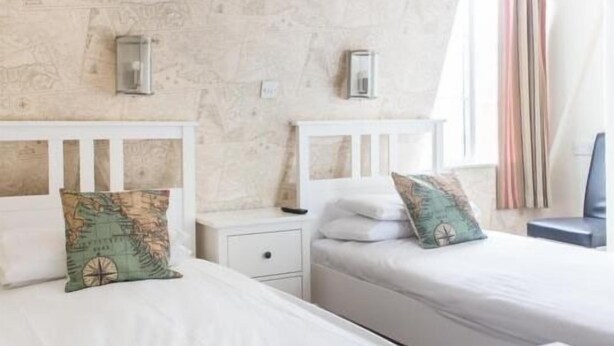 A room with two beds, each with a white headboard and a map-themed pillow. - The Anchor Inn (Cowes)