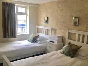 A twin room with two beds, a window with curtains, and a wall-mounted light fixture.