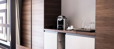 Una cocina moderna con cafetera, cristalería y una pared de acento de madera.
