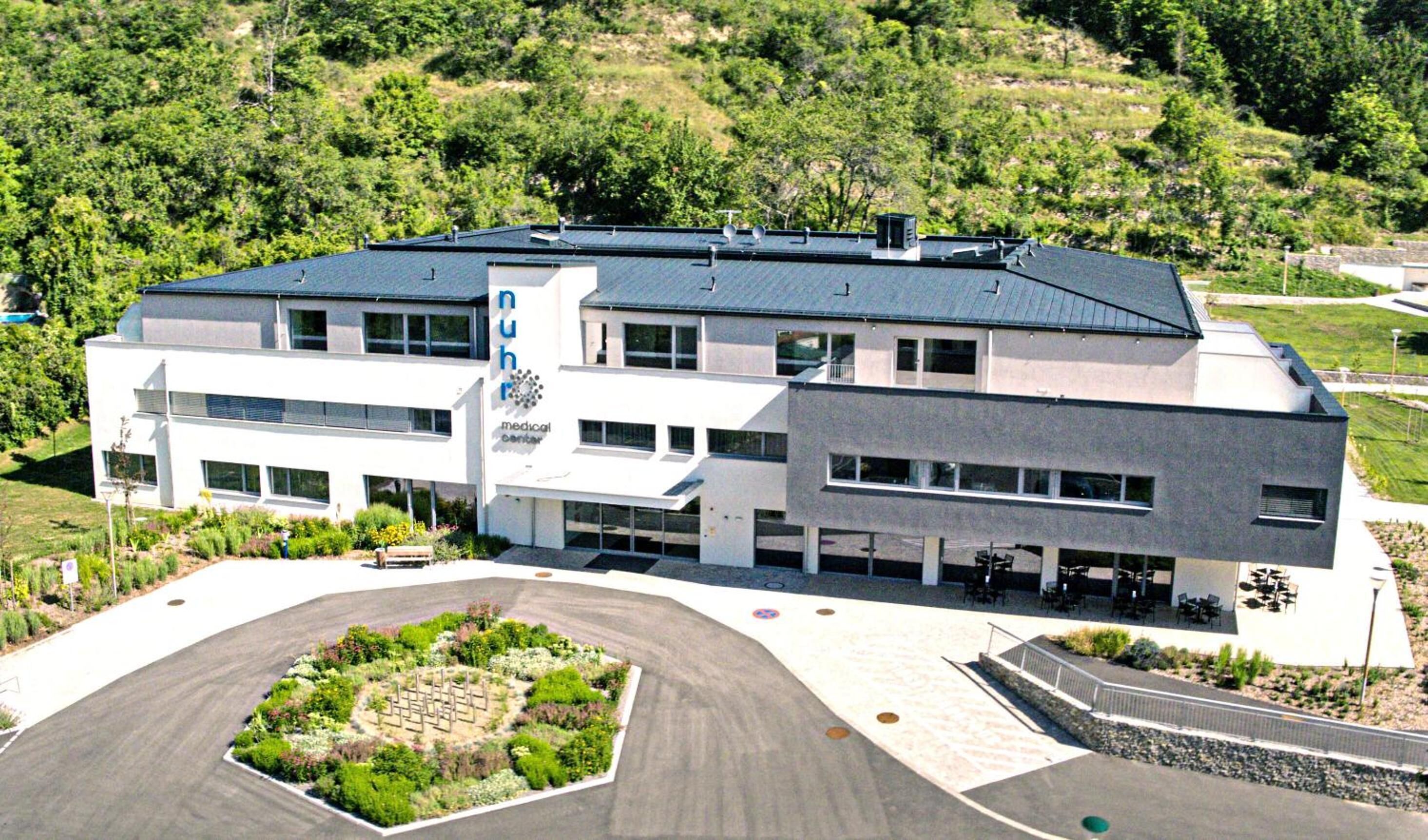 A modern medical center with a central courtyard, multiple entry points, and a landscaped garden.