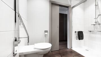 A modern bathroom with a toilet, a shower, and a glass door leading to another room.